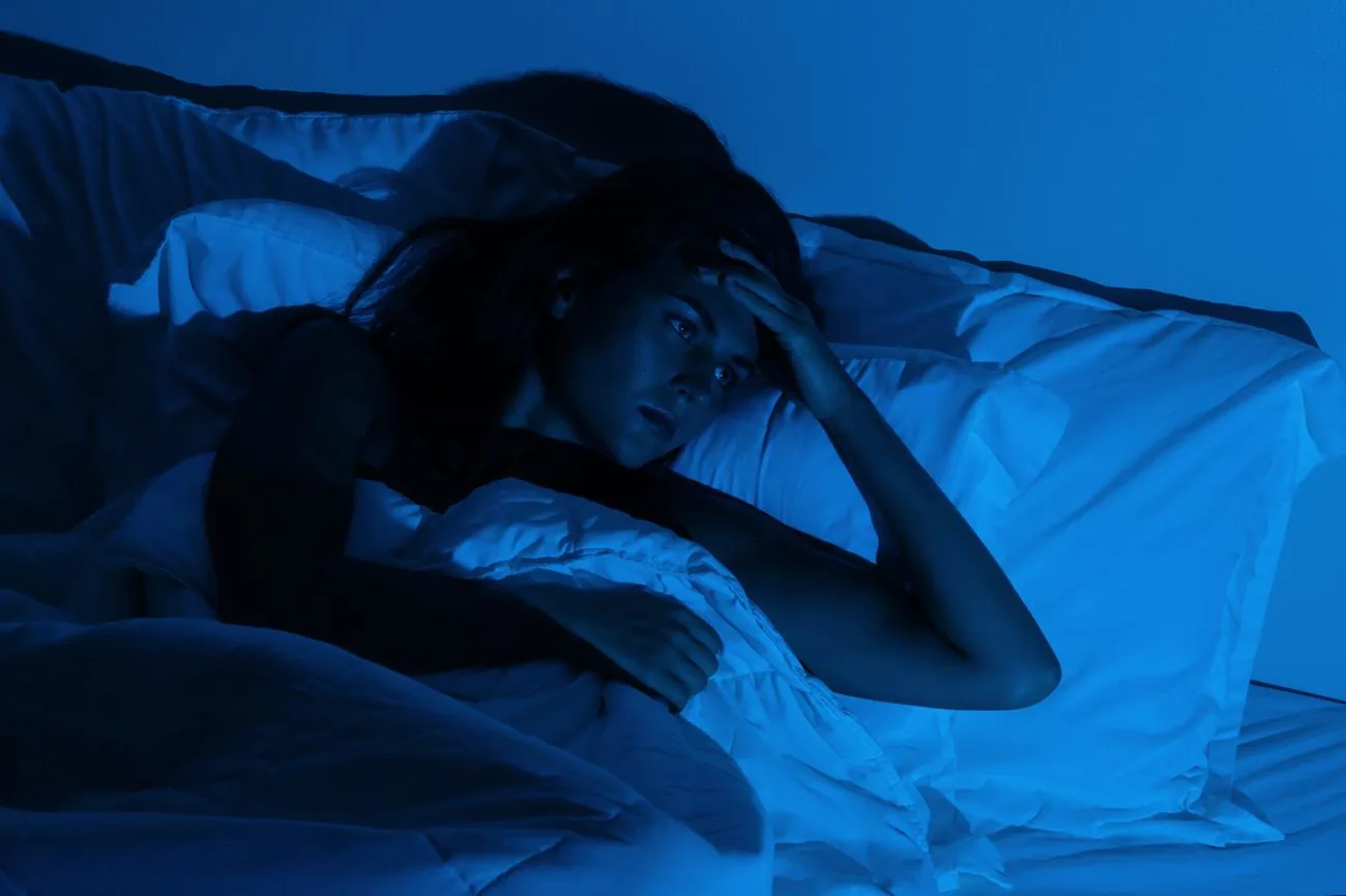 L’insomnie Femme éveillée dans son lit la nuit, illustrant l’insomnie